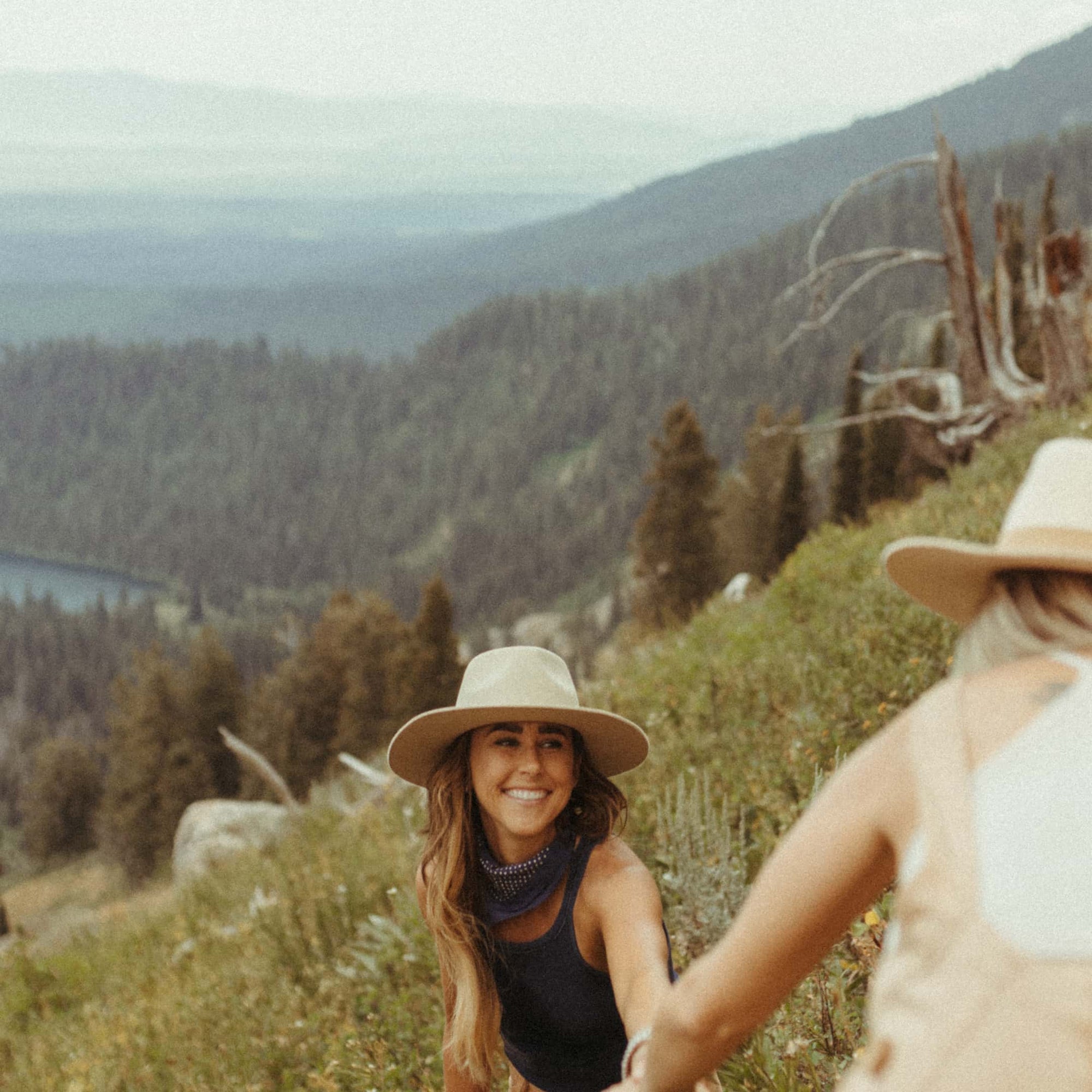 Taryn holding Amanda's hand while they hike up a mountain