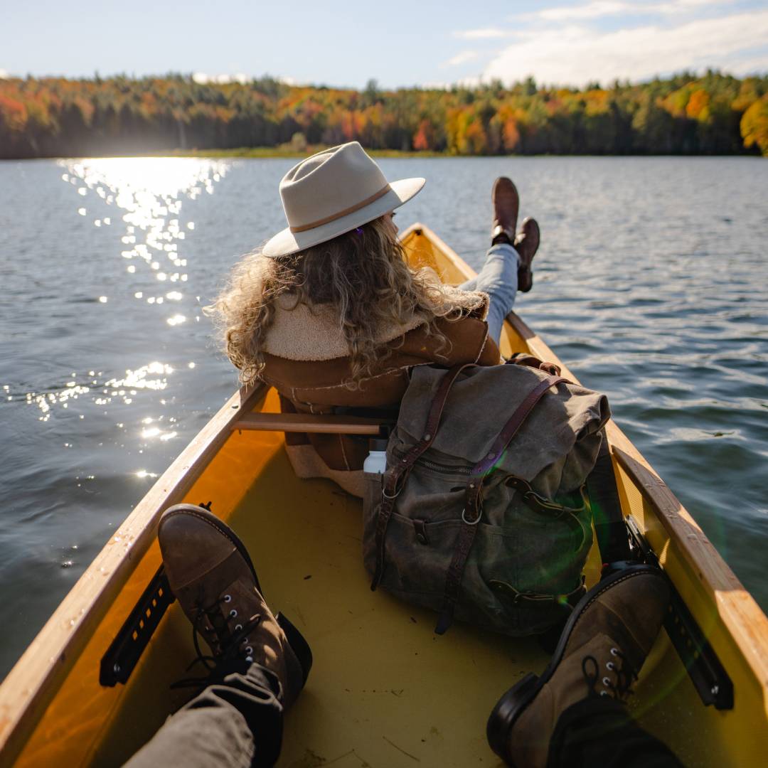 Chelsea sits at the front of a canoe and her feet are hanging out, Braydens feet are visible in the foreground, inside the canoe.