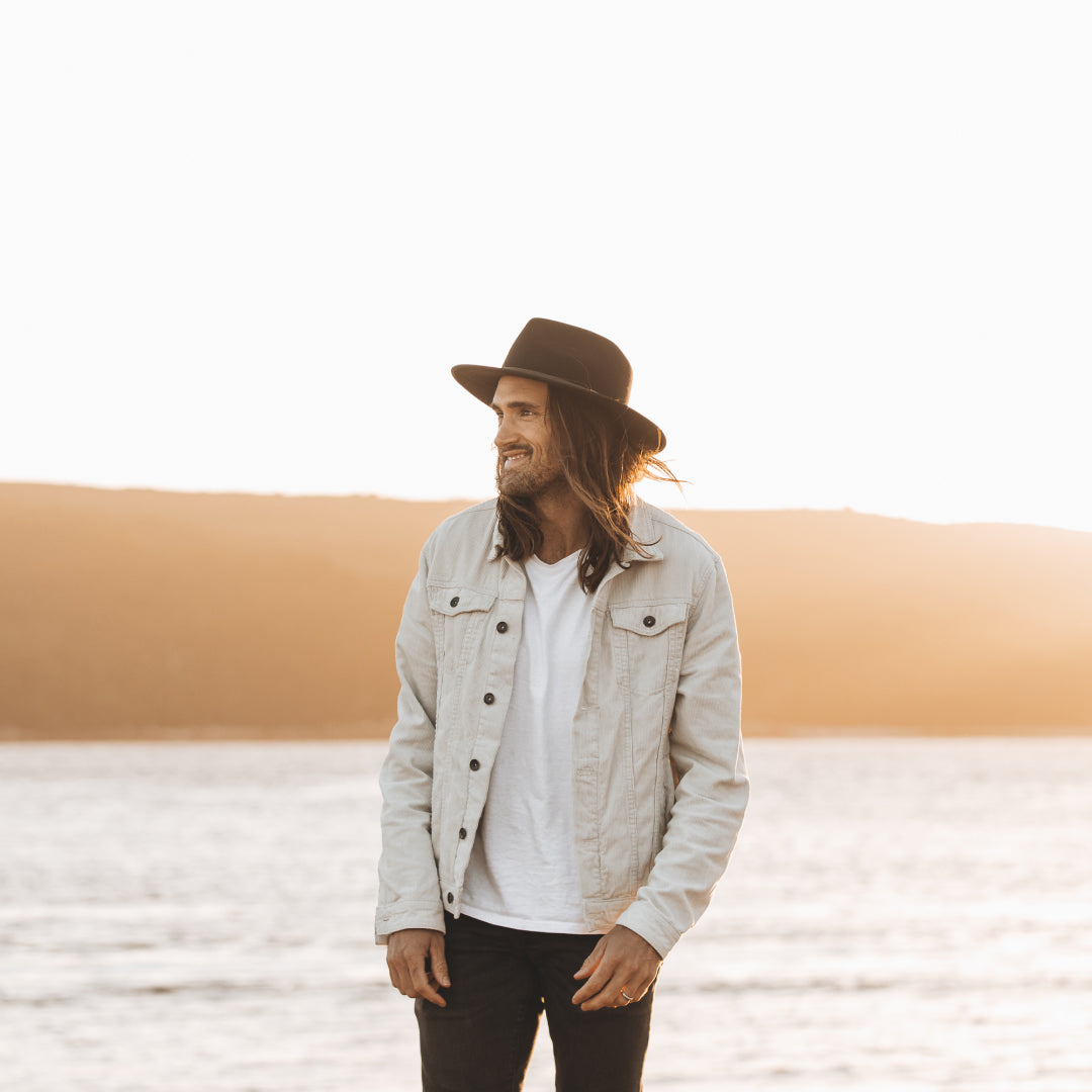 Alex smiling and standing in front of the ocean