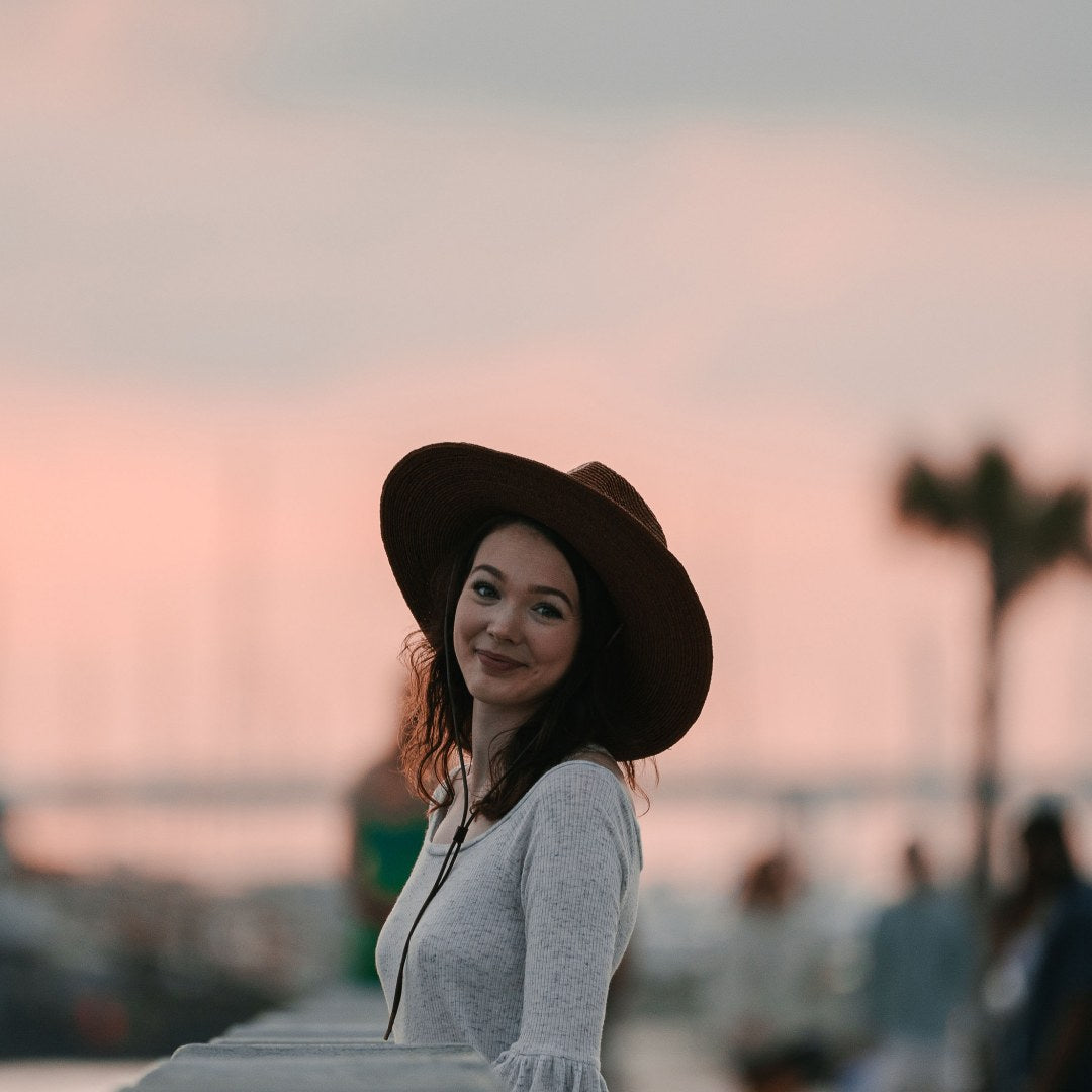 A young woman walking along a boardwalk at sunset