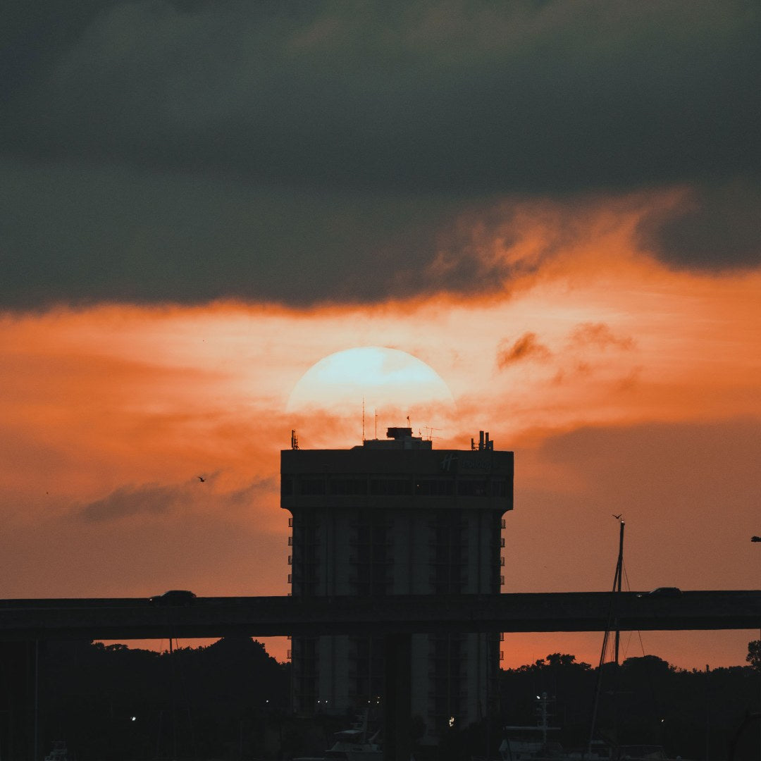 A building silhouetted against the sun setting in the background