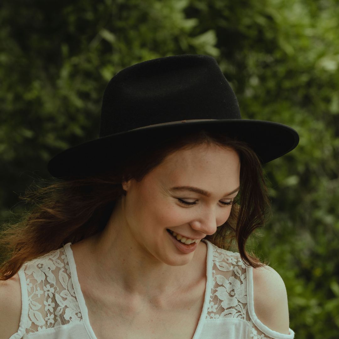 Close up of a young woman wearing a hat while walking through a garden