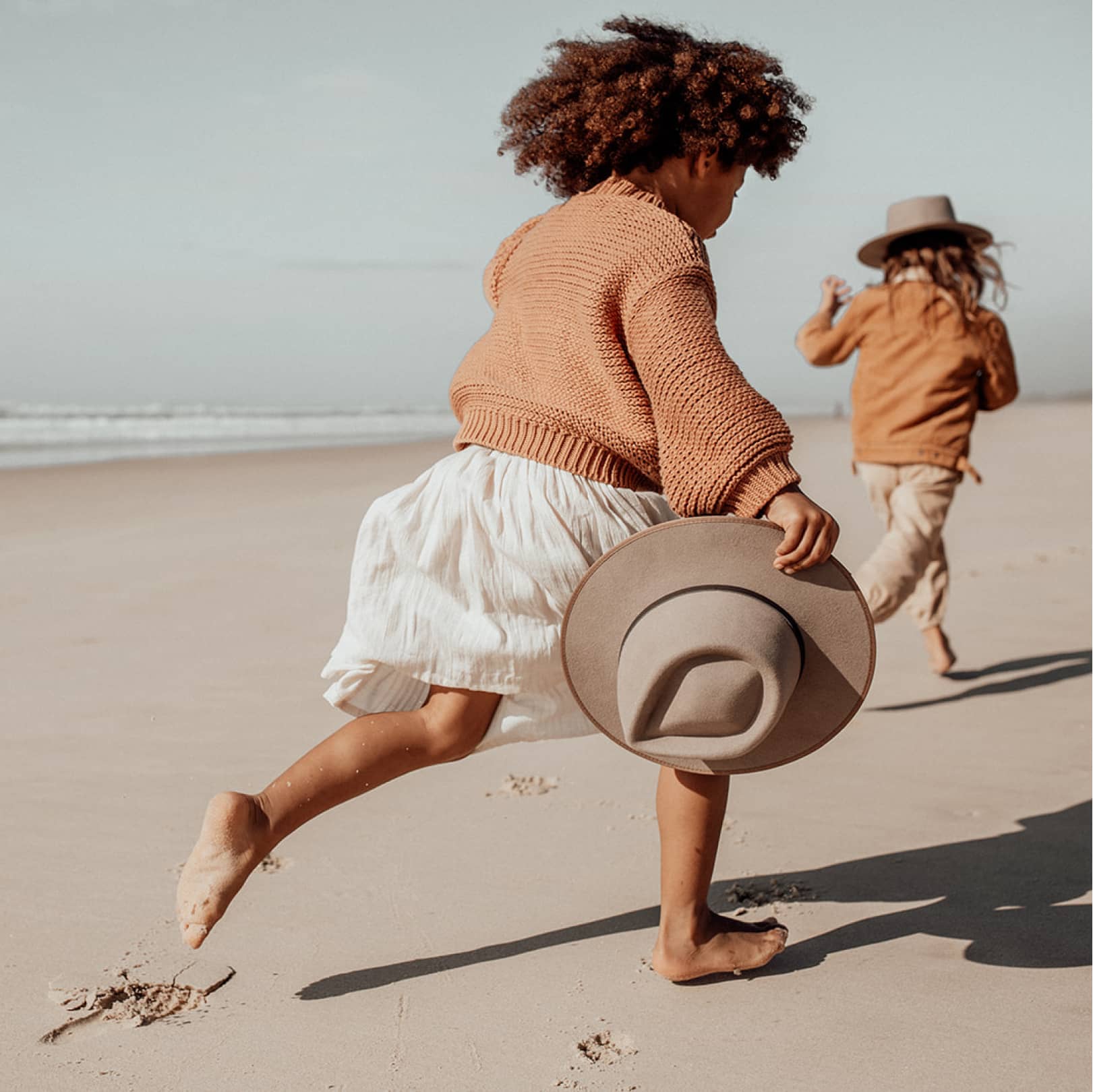 Two children running along the sand at the beach in Byron Bay