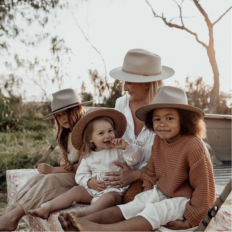 A woman sitting with her children on the back tray of a ute