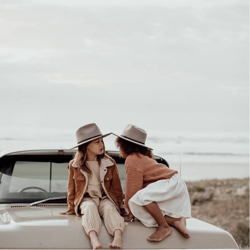 Two children sitting on the bonnet of a car