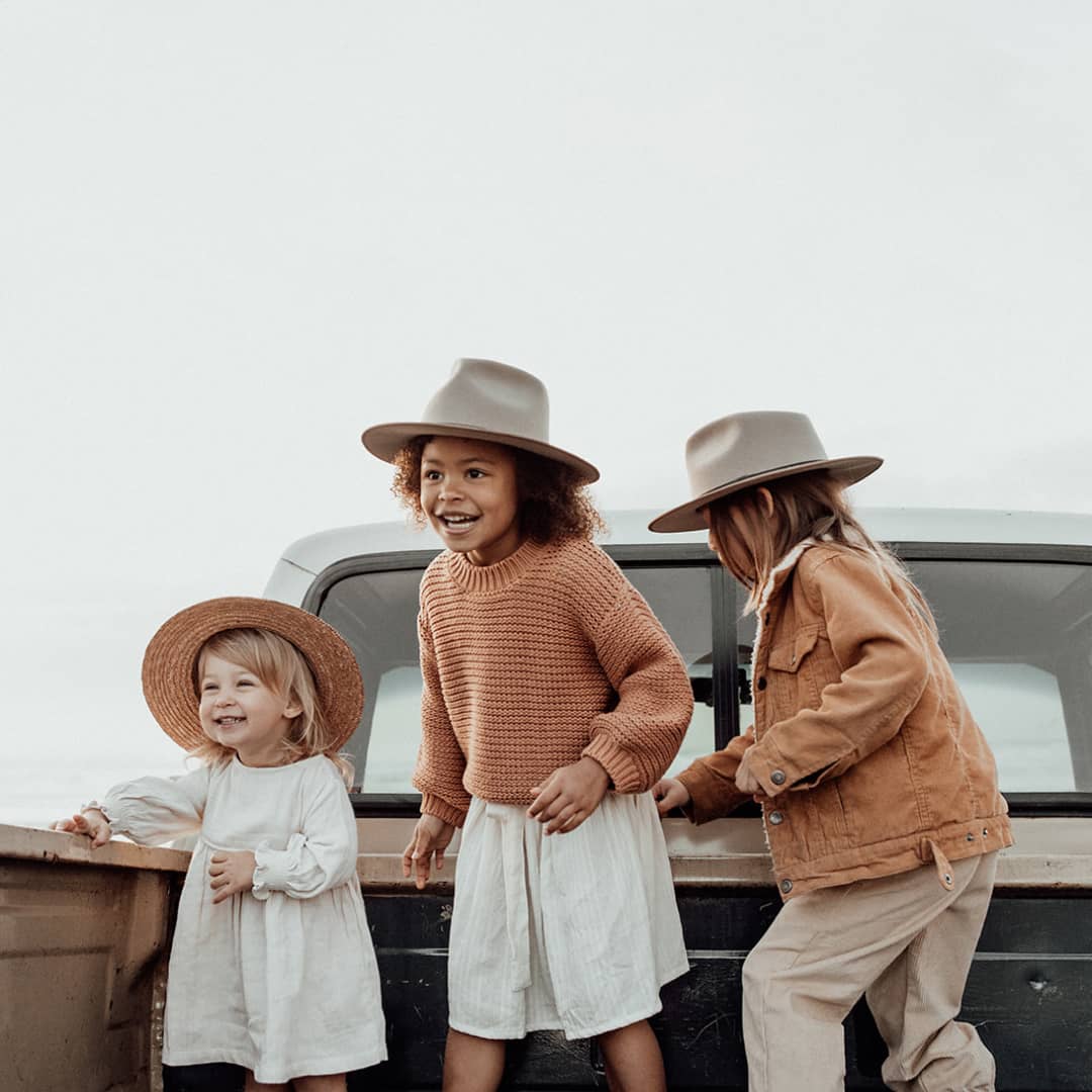 Three children playing in the tray of the back of a ute