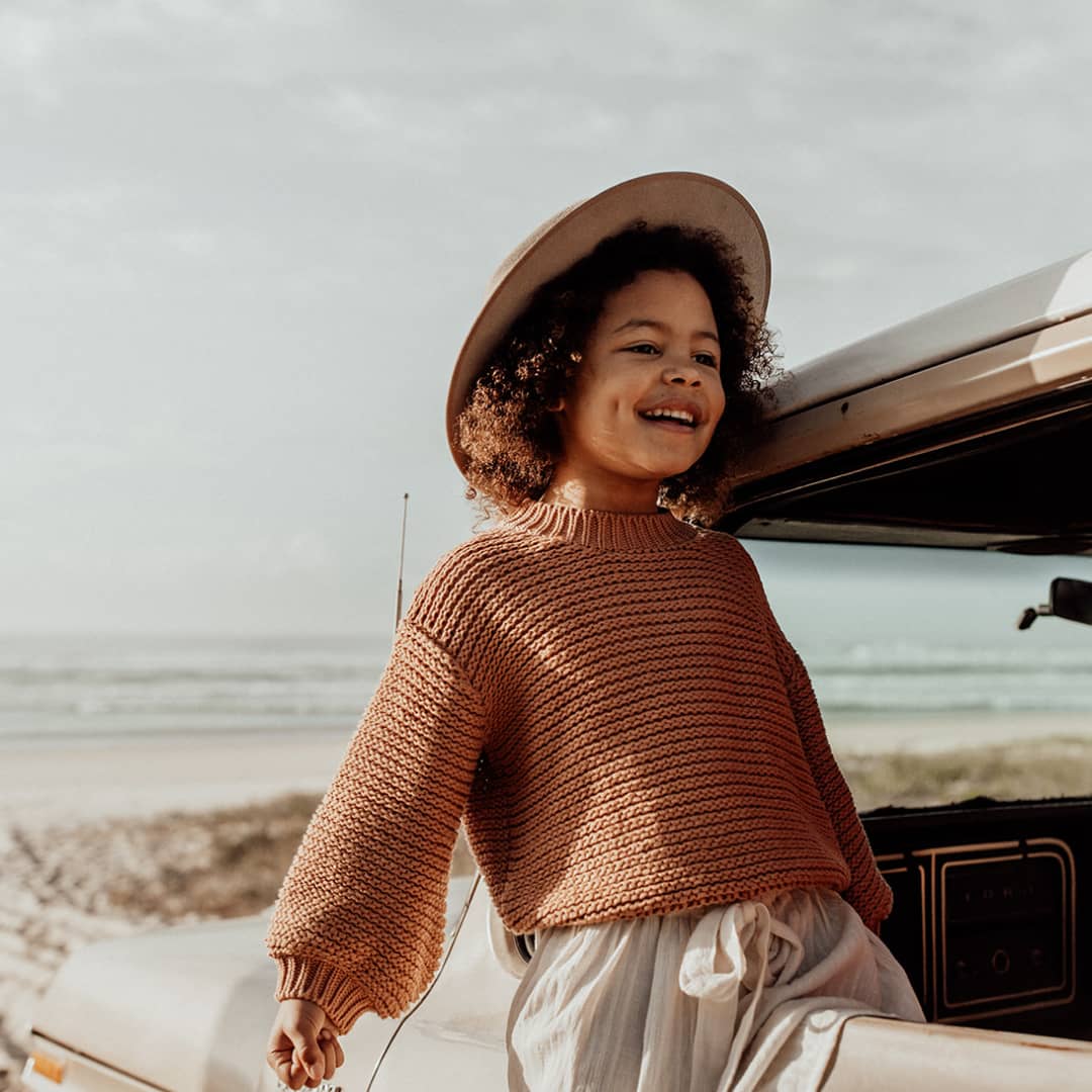 Child wearing a wide brim wool hat looking out the window of a ute