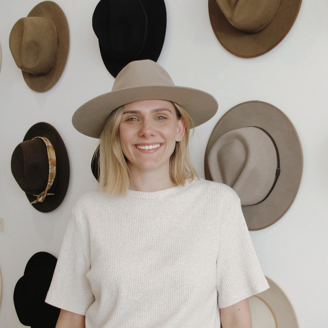 A woman with short blonde hair wearing a wide brim wool hat