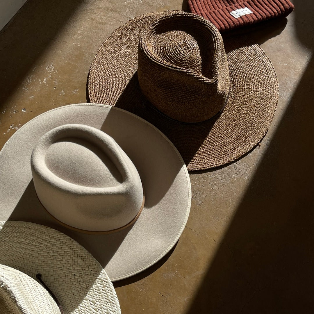Close up of Will & Bear hats laid out together in the sun