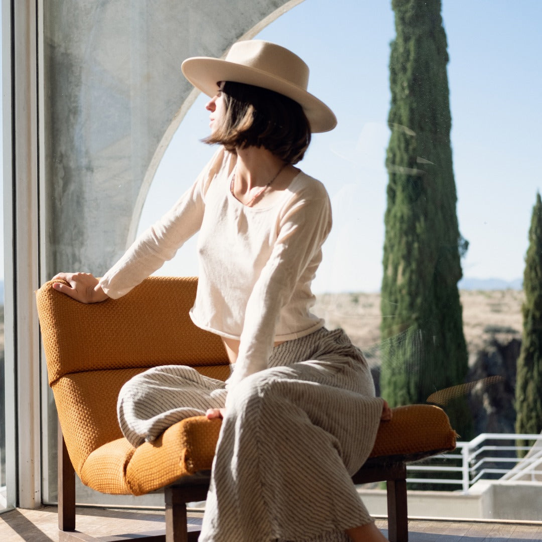 Lucette sitting on a chair next to a circular window in Arcosanti