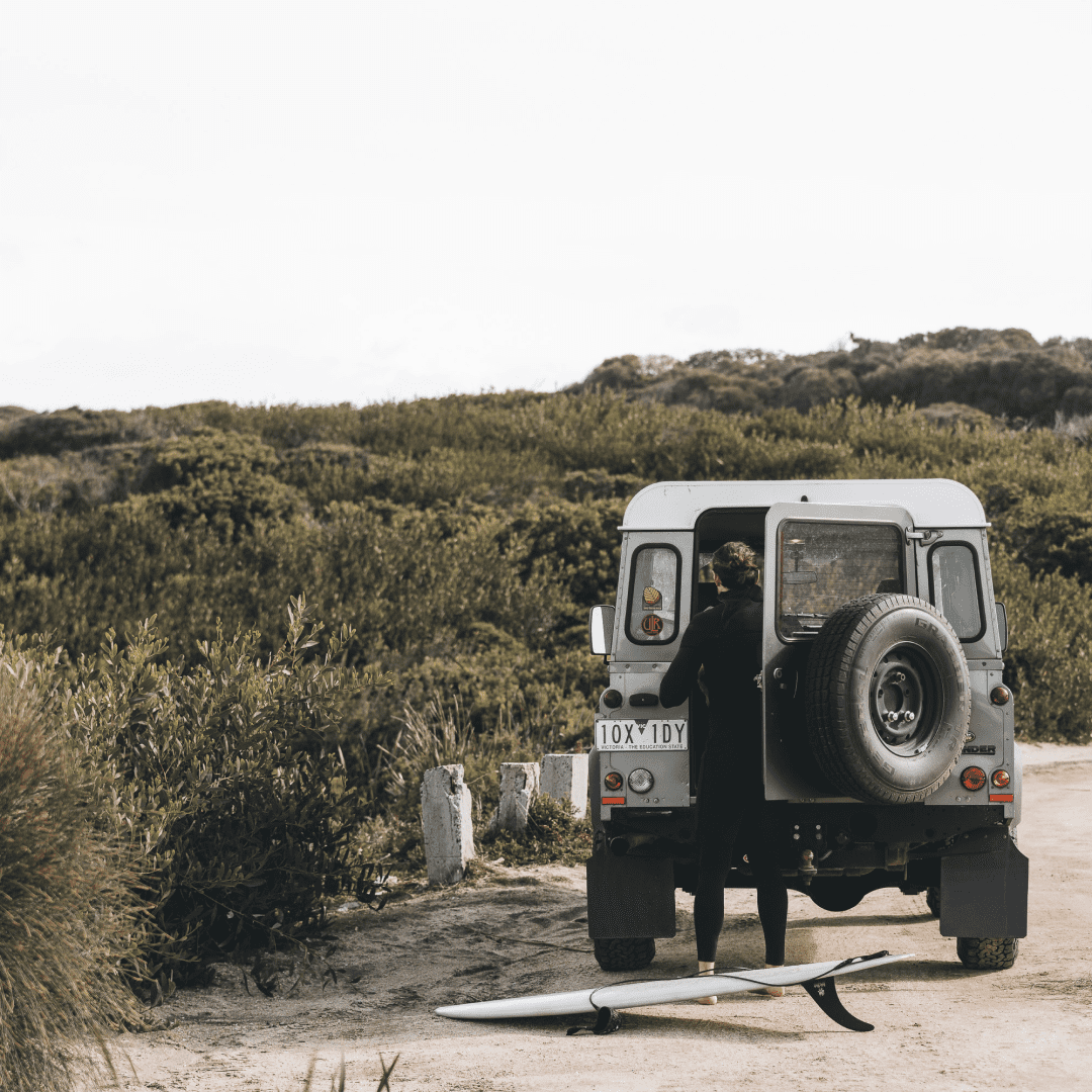 Alex grabbing his surf board out the back of a 4wd ready to go for a surf