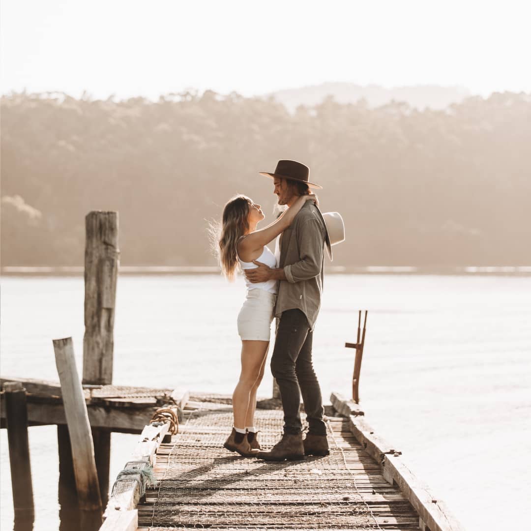 Lauren and Alex standing on a jetty wearing wide brim wool hats