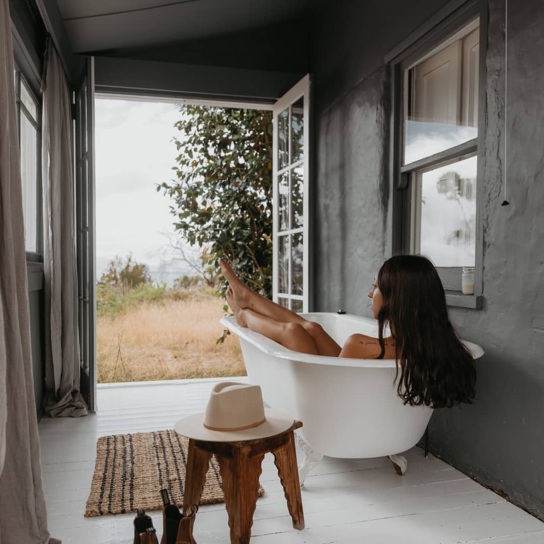 Woman sitting in a bath with a view inside a cabin