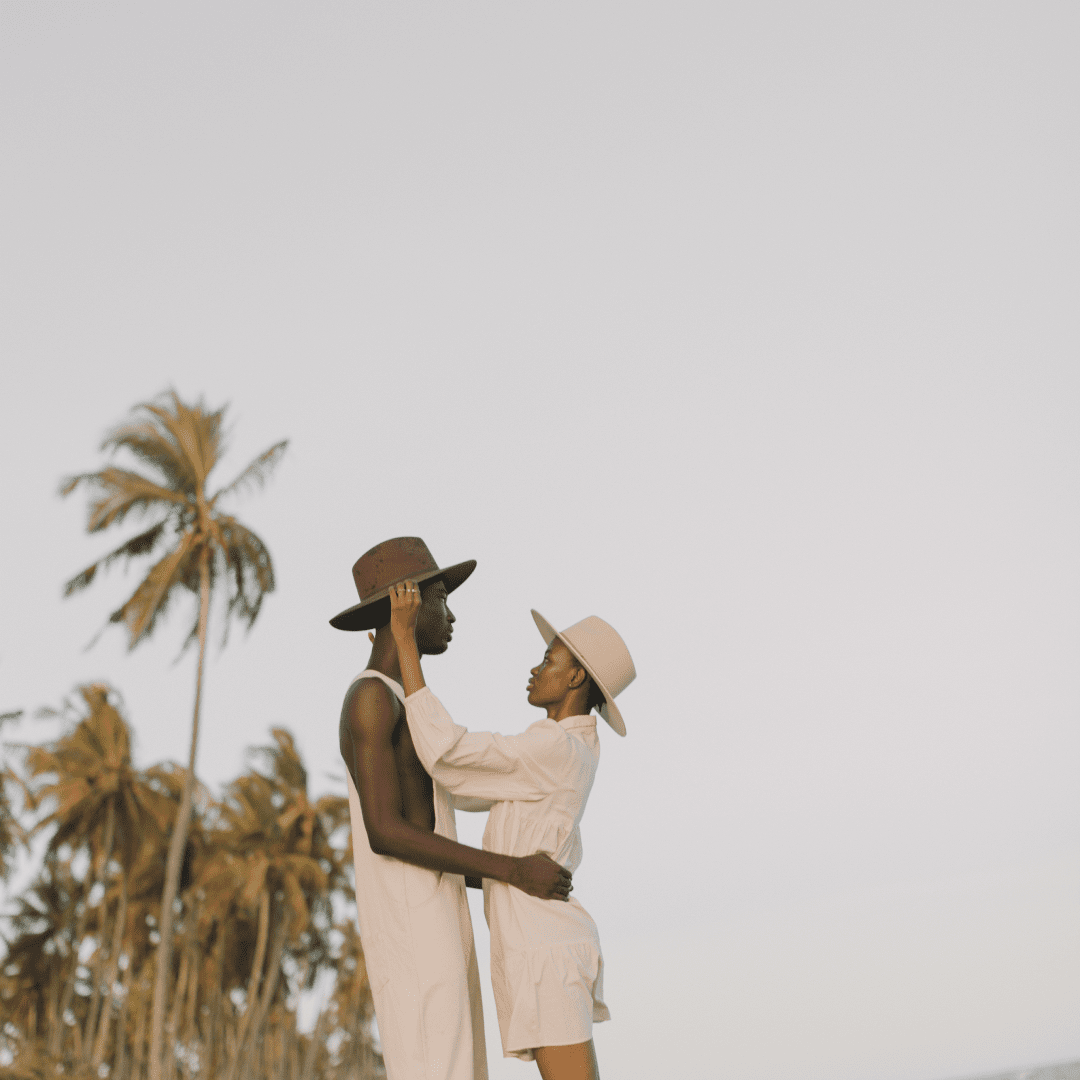 A man and woman wearing wide brim wool hats at the beach