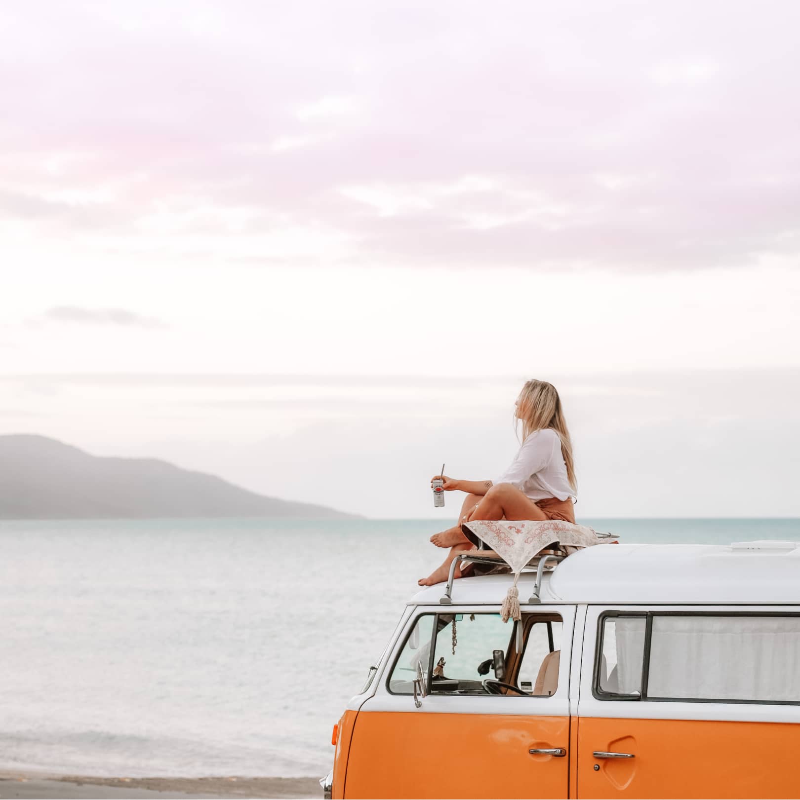 Tia sitting on her van Stella looking out at the ocean