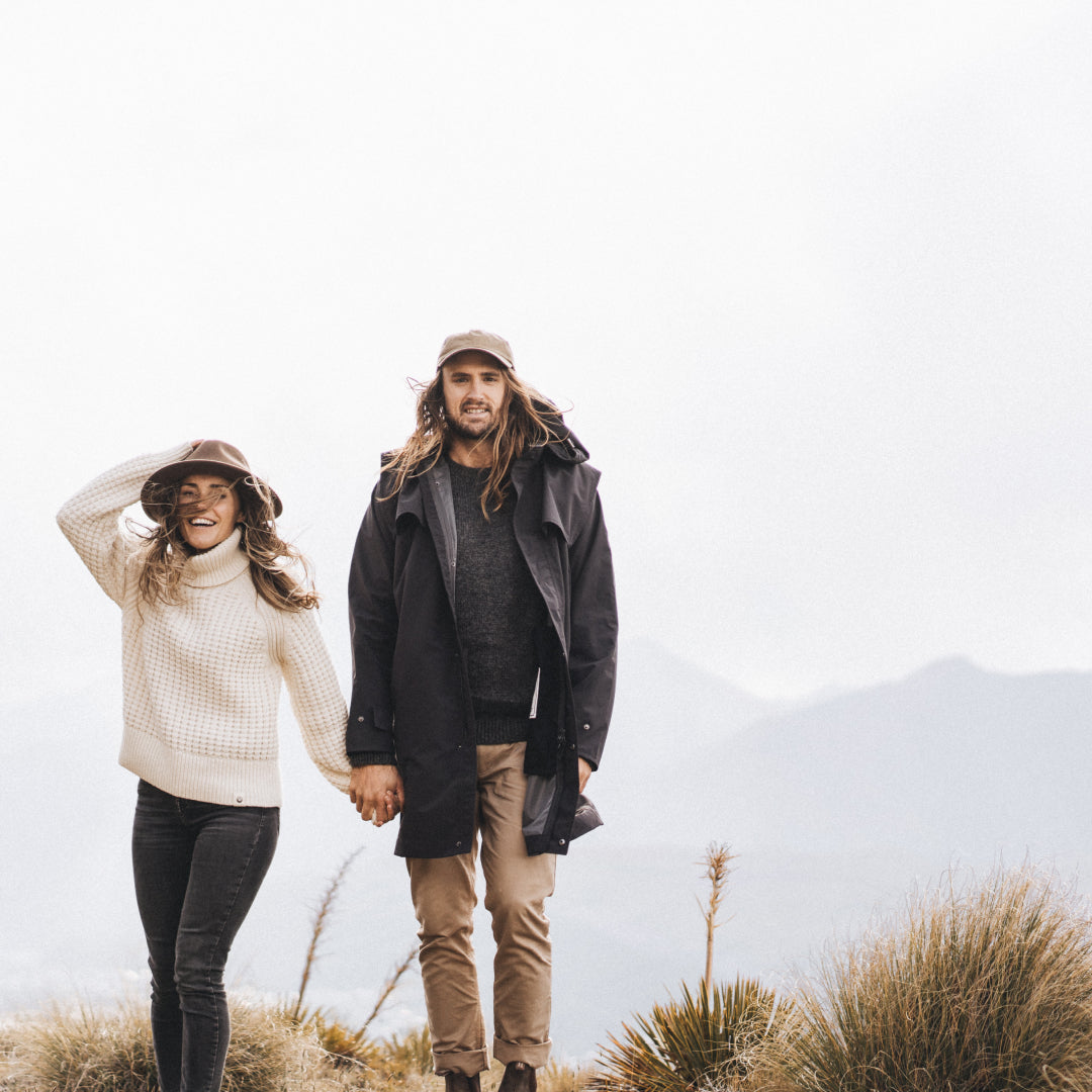 Alex and Loz holding hands standing on top of a mountain peak