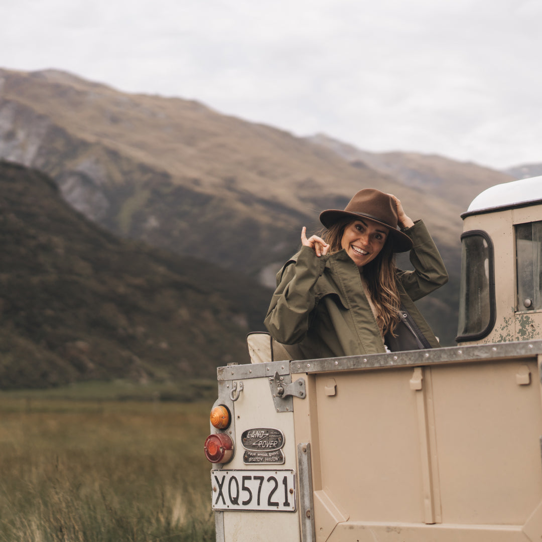 Loz smiling and waving at the camera while she sits in the back of a Land Rover tray