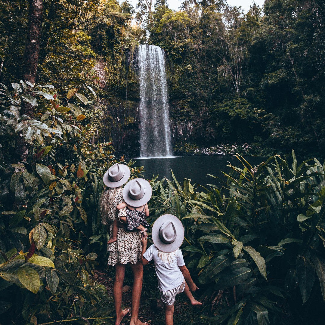 Mother standing in front of a water fall with her children wearing hats
