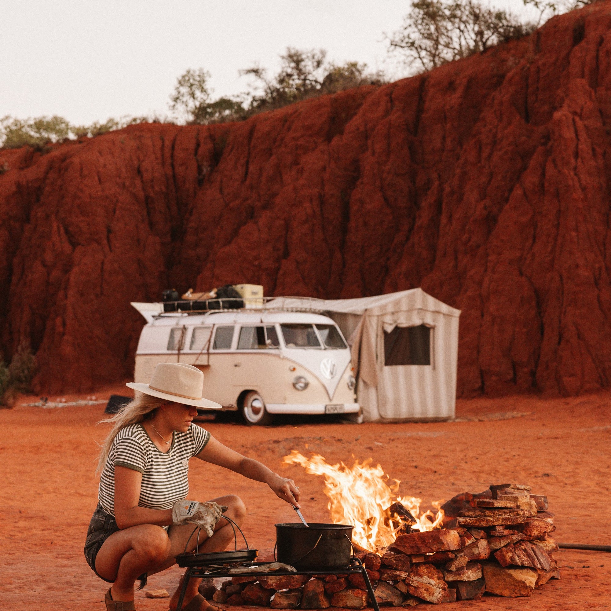 Kirianna cooking over the fire with Uluru and her van in the background