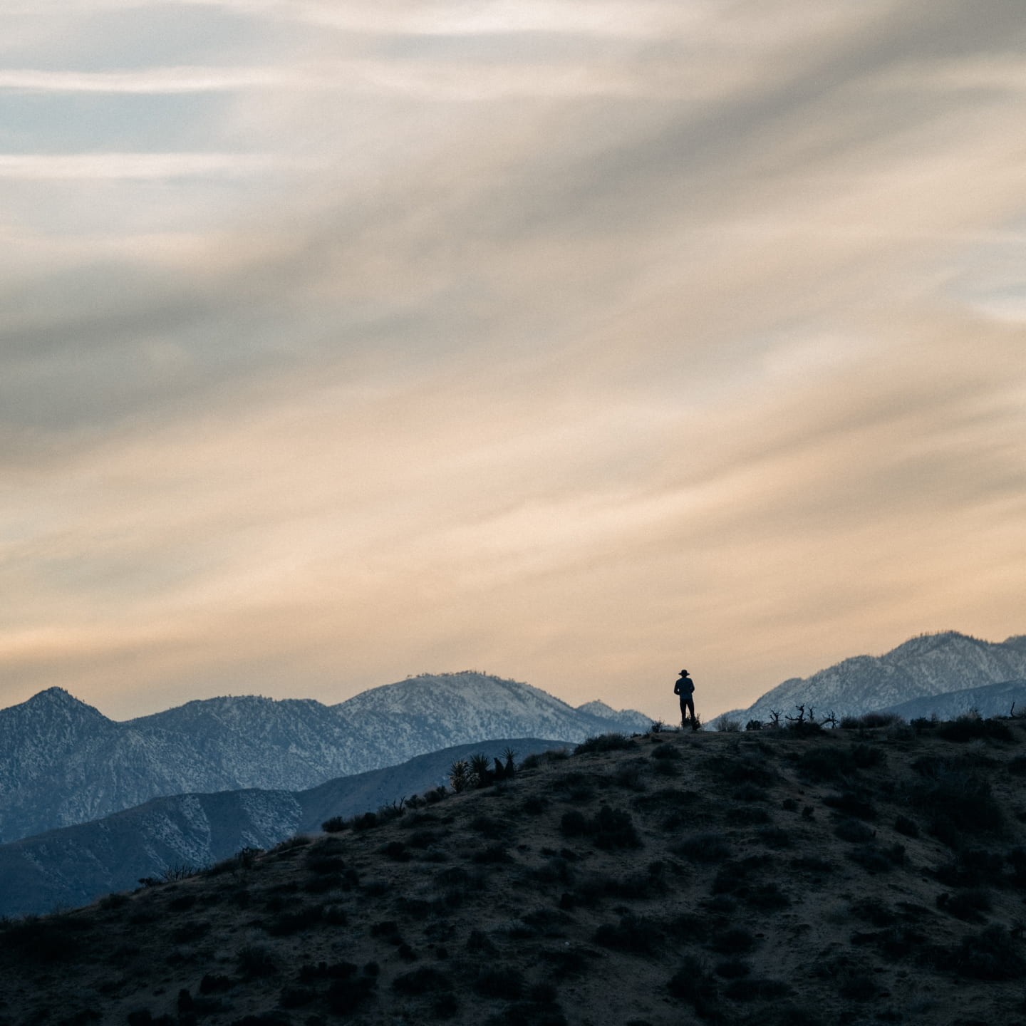 A silhouetted image of William standing on top of a mountain as the sun is setting