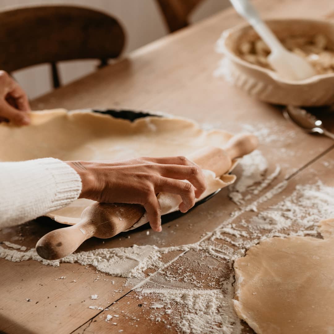 Close up of some one rolling out dough on a baking tray with a rolling pin