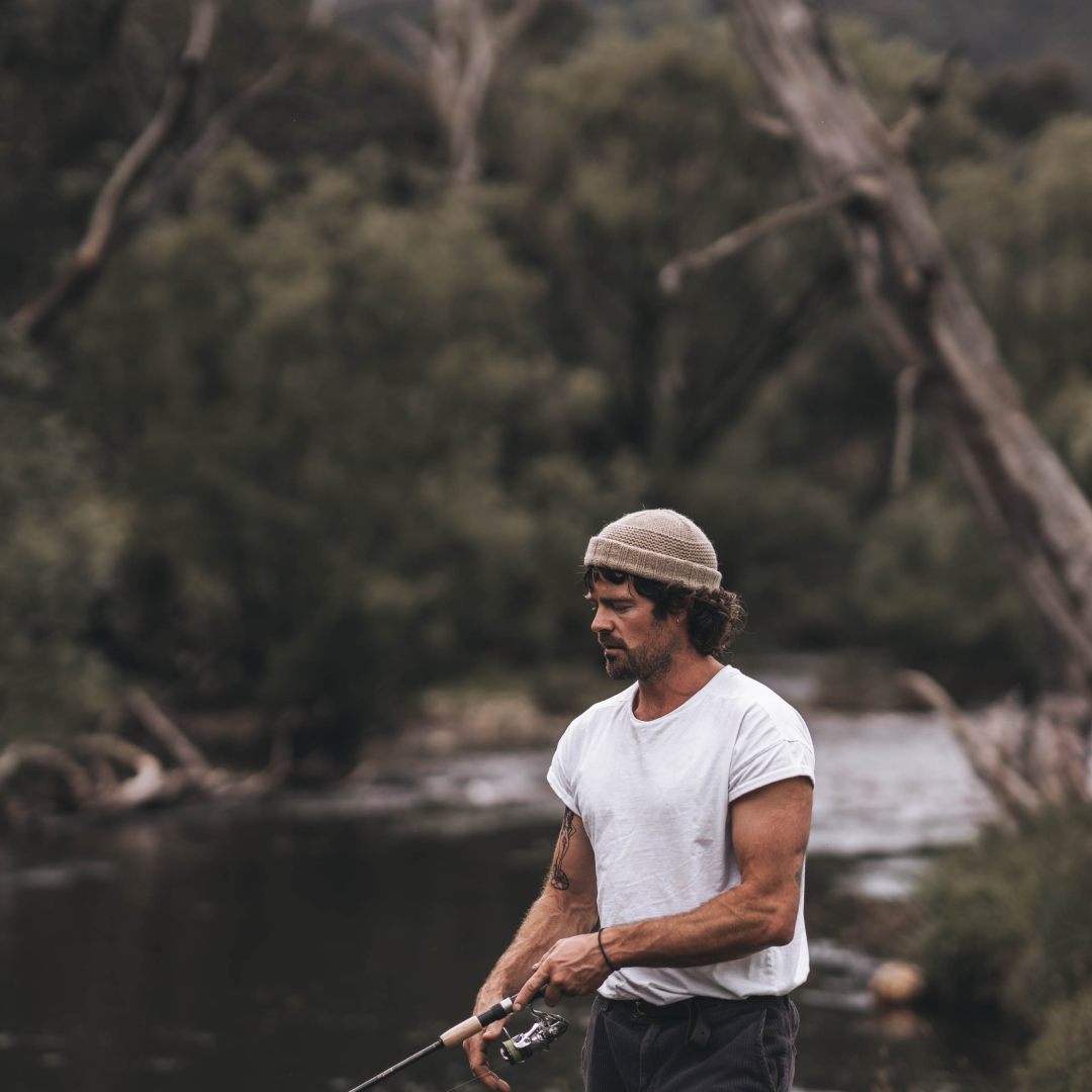 A man wearing a Doc Fawn beanie while fishing