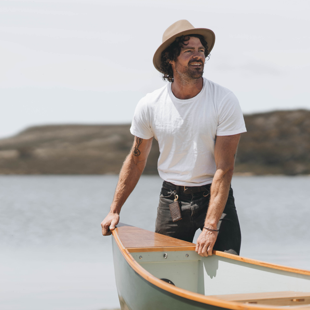 Man pushing out a canoe, wearing a William Oak wide brim wool hat