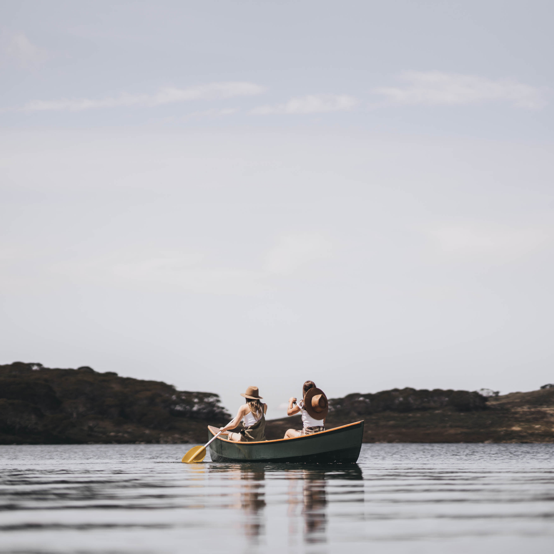 Two women wearing wide brim sun hats while canoeing