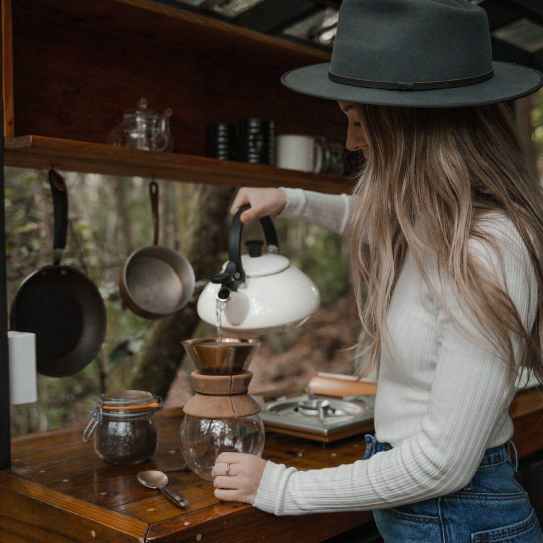 Melissa making a filter coffee inside a tree house cabin