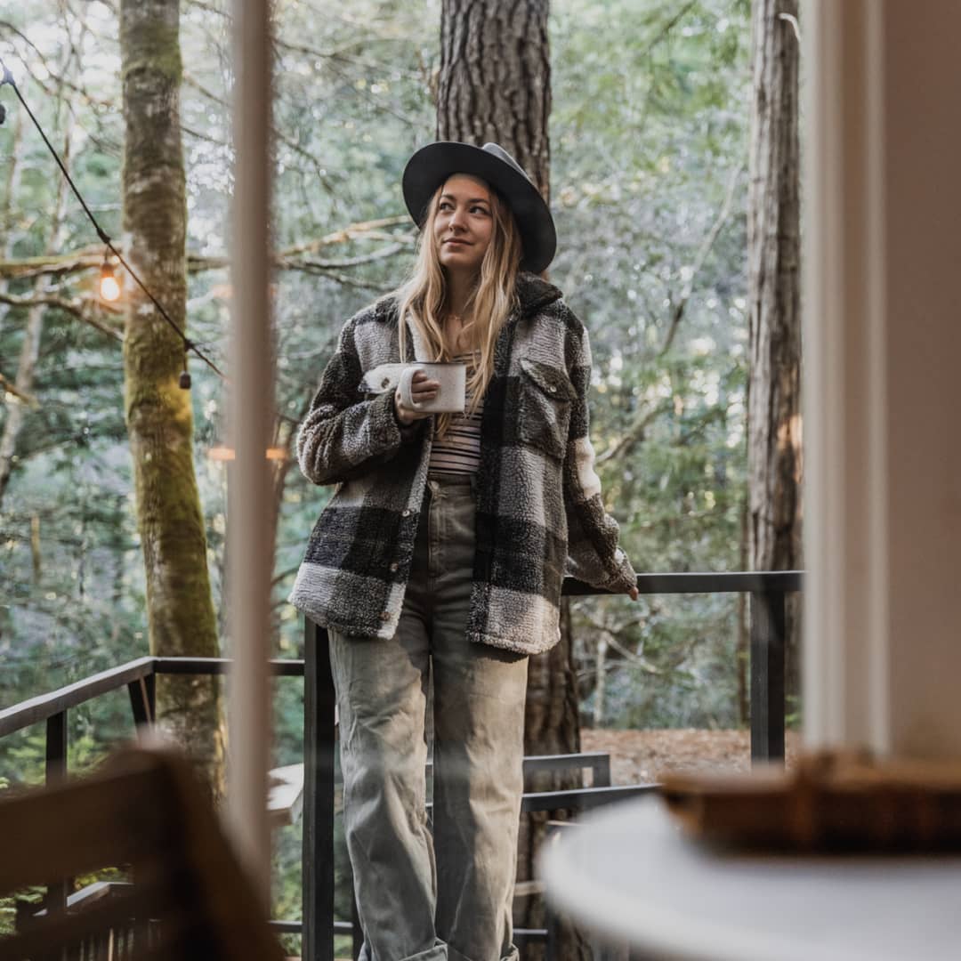 Melissa standing on an outdoor deck holding a cup of hot coffee