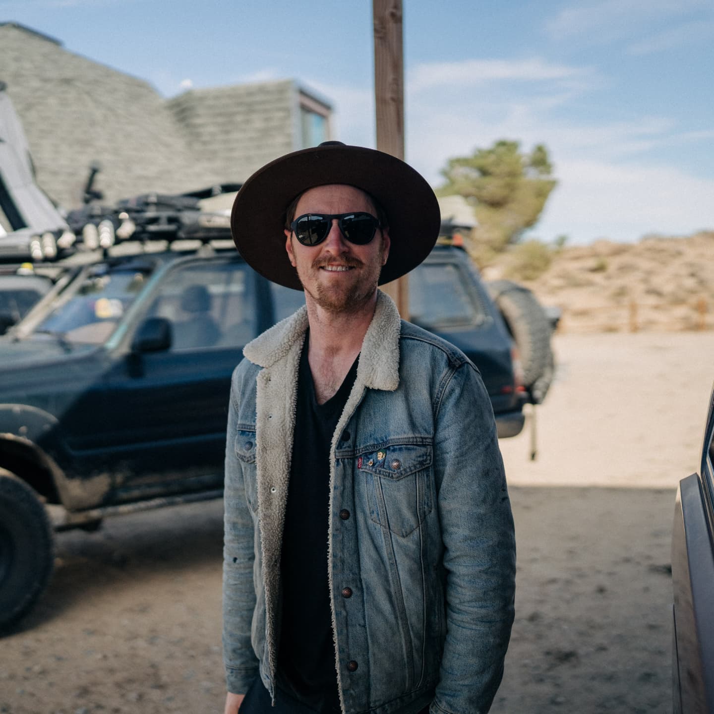 William standing in front of his SUV in Joshua Tree wearing a wide brim hat