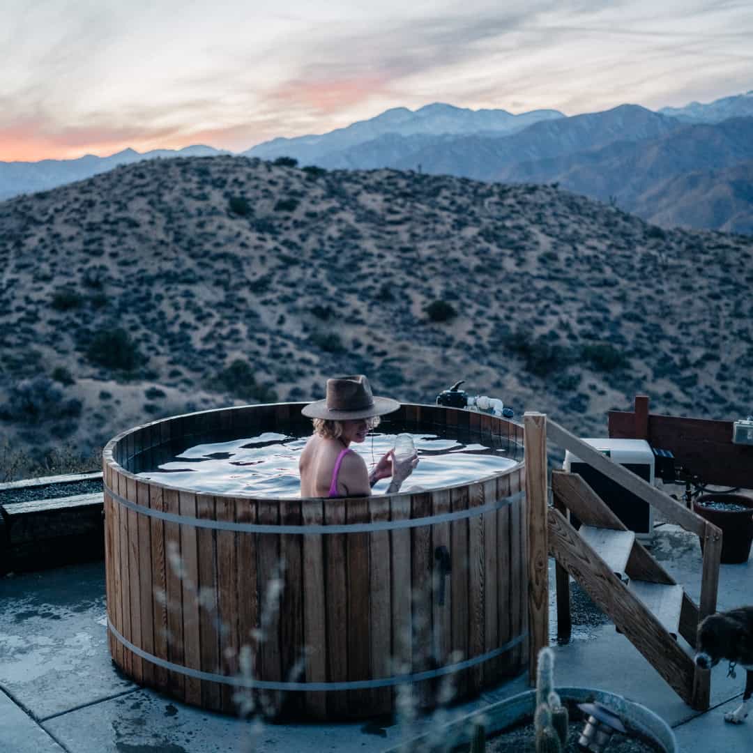 A woman sitting in a wooden outdoor bath in Joshua Tree