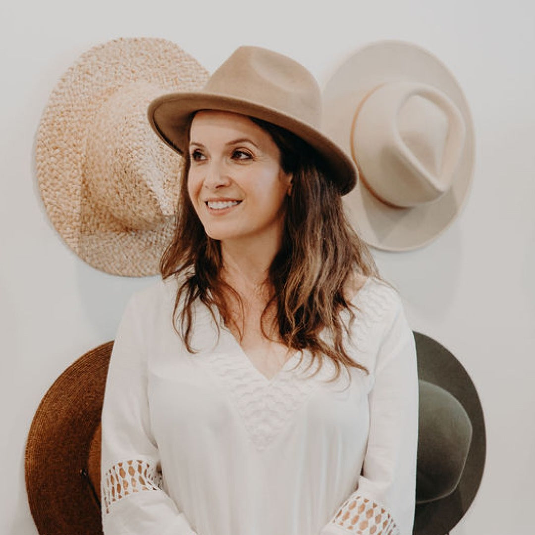 A woman with long brown hair wearing a wide brim wool felt fedora