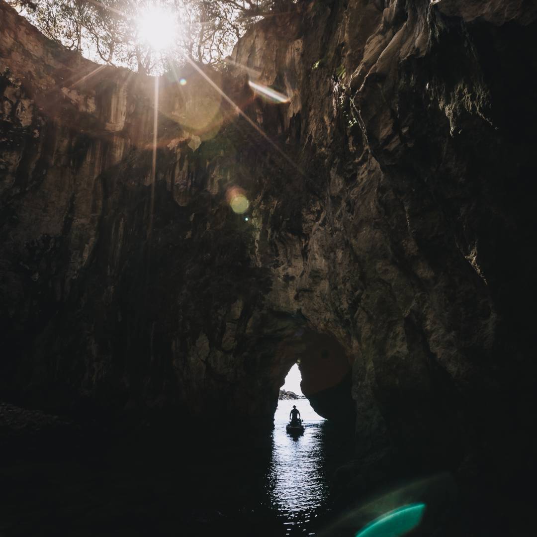 A man is on a jet-ski driving through a cave entrance back out