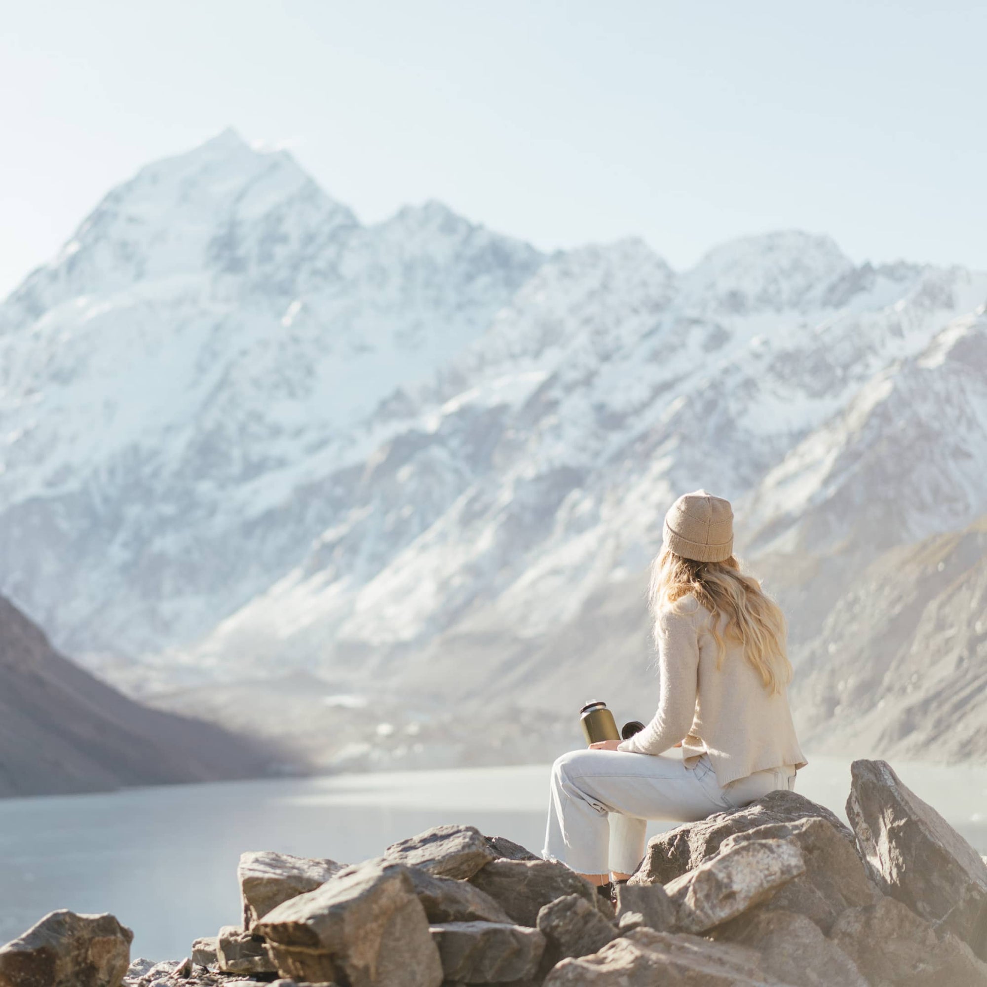 A woman sits on a rock looking at the mountain views
