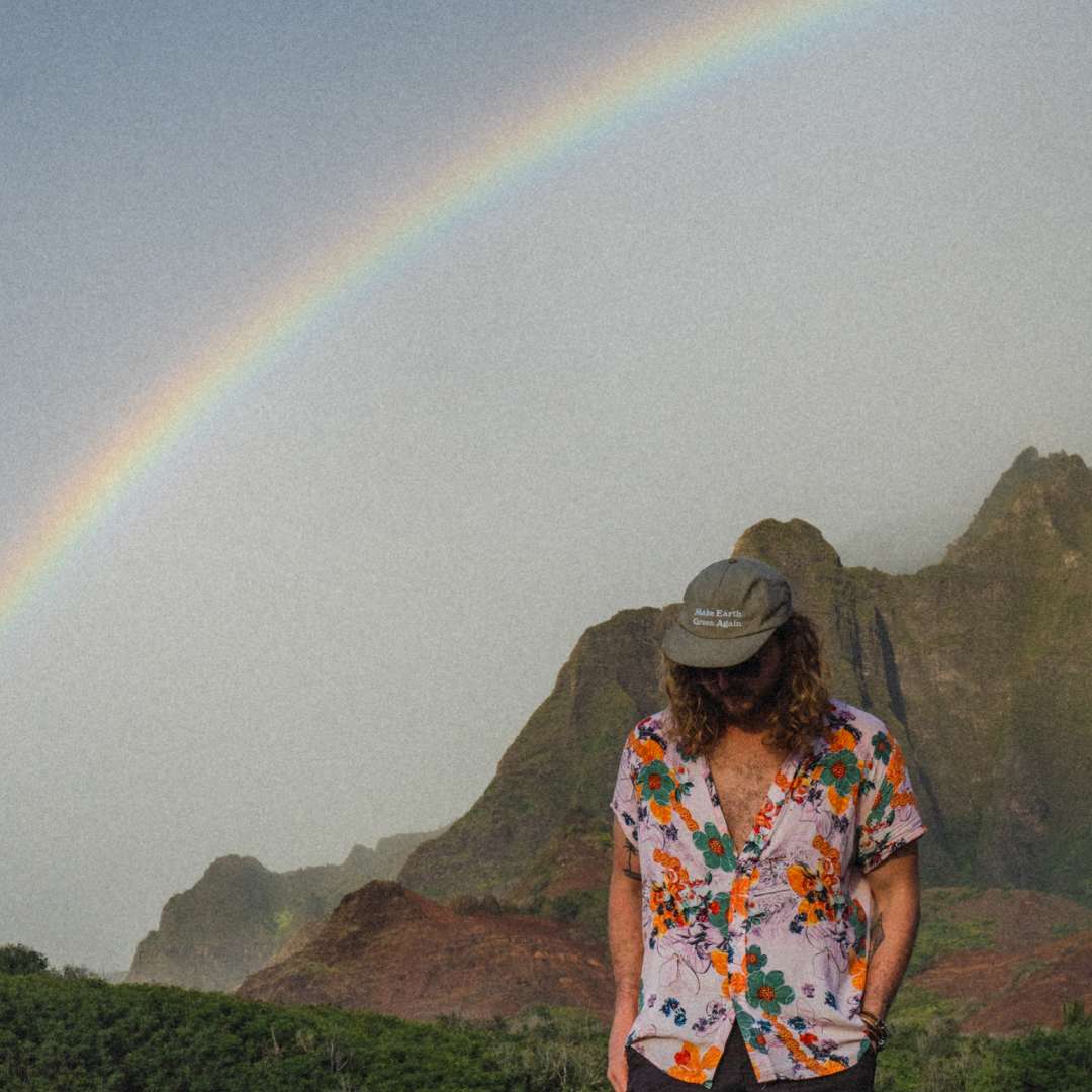 Brayden walking along the NePali coast with a rainbow behind him