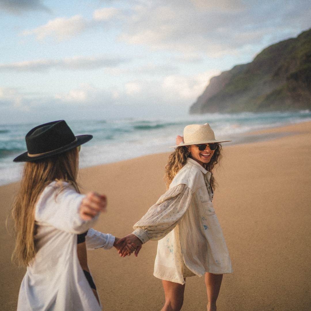 Chelsea and Steph holding hands while walking along the beach