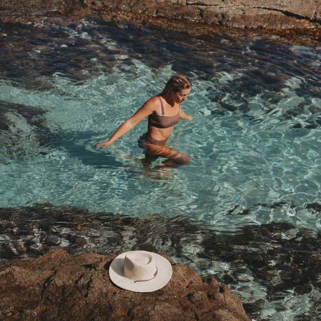 Kendall swimming in waist deep water in a rock pool