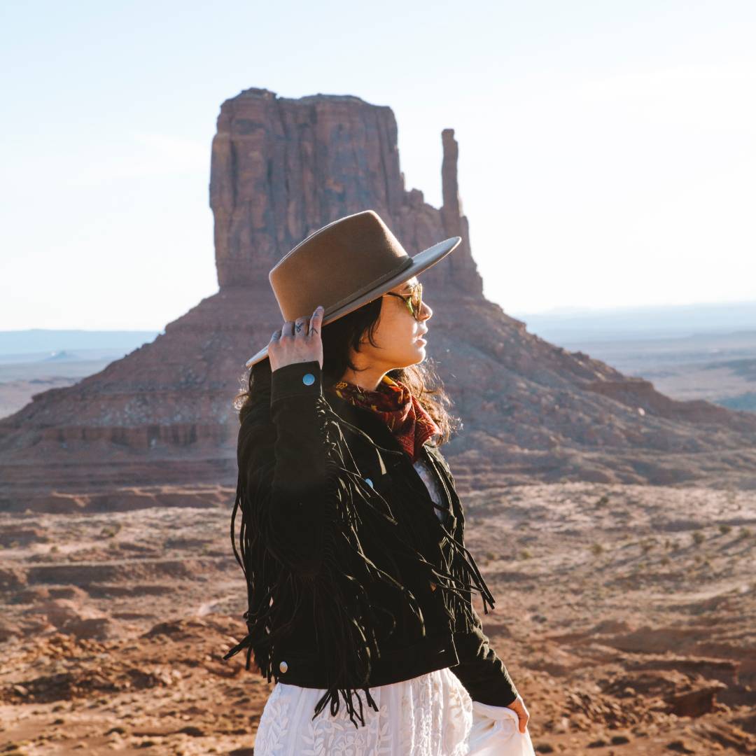 Woman with log black hair wearing a wide brim hat out in the Utah desert
