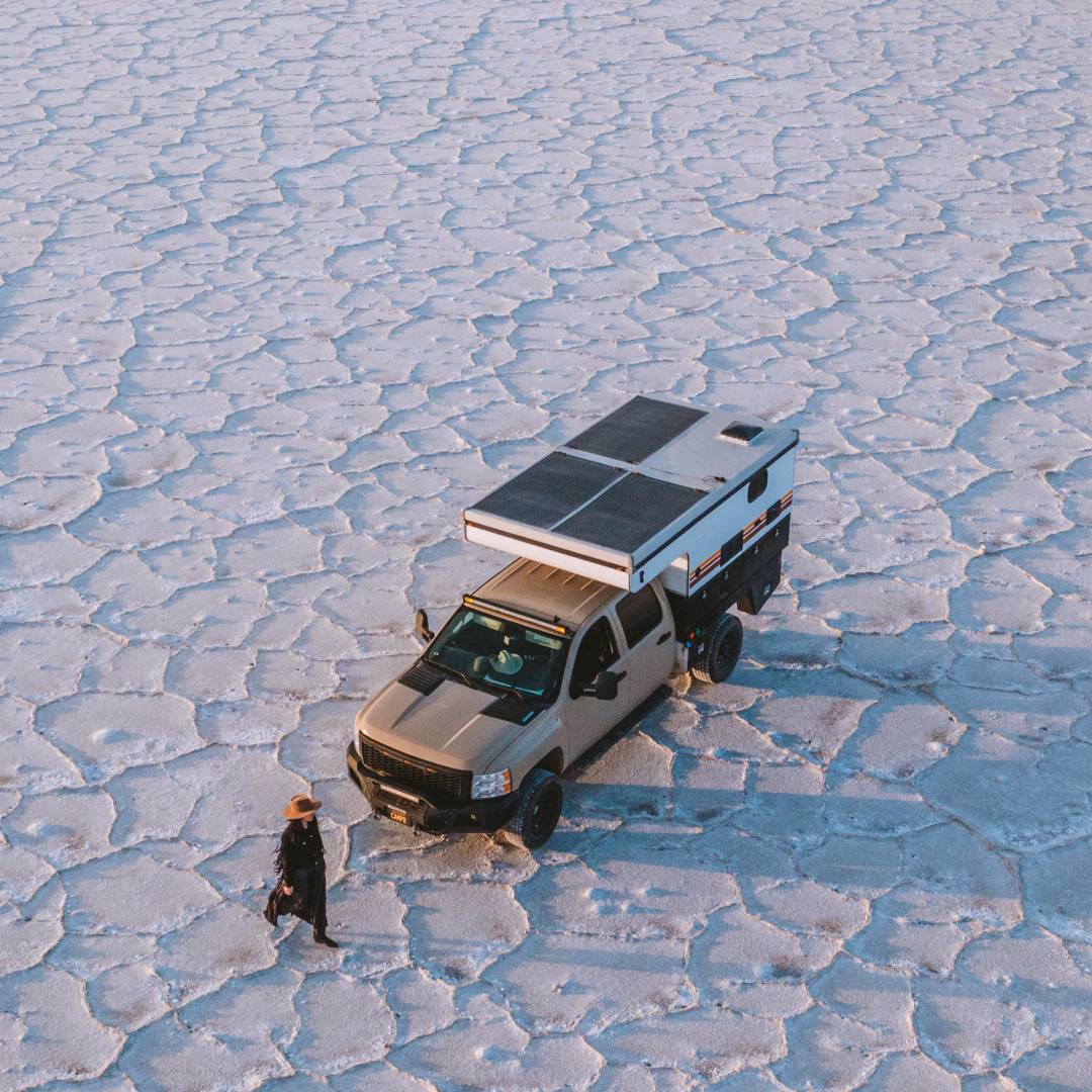Aerial photo of Blanca walking past their camper van in the middle of a salt flat