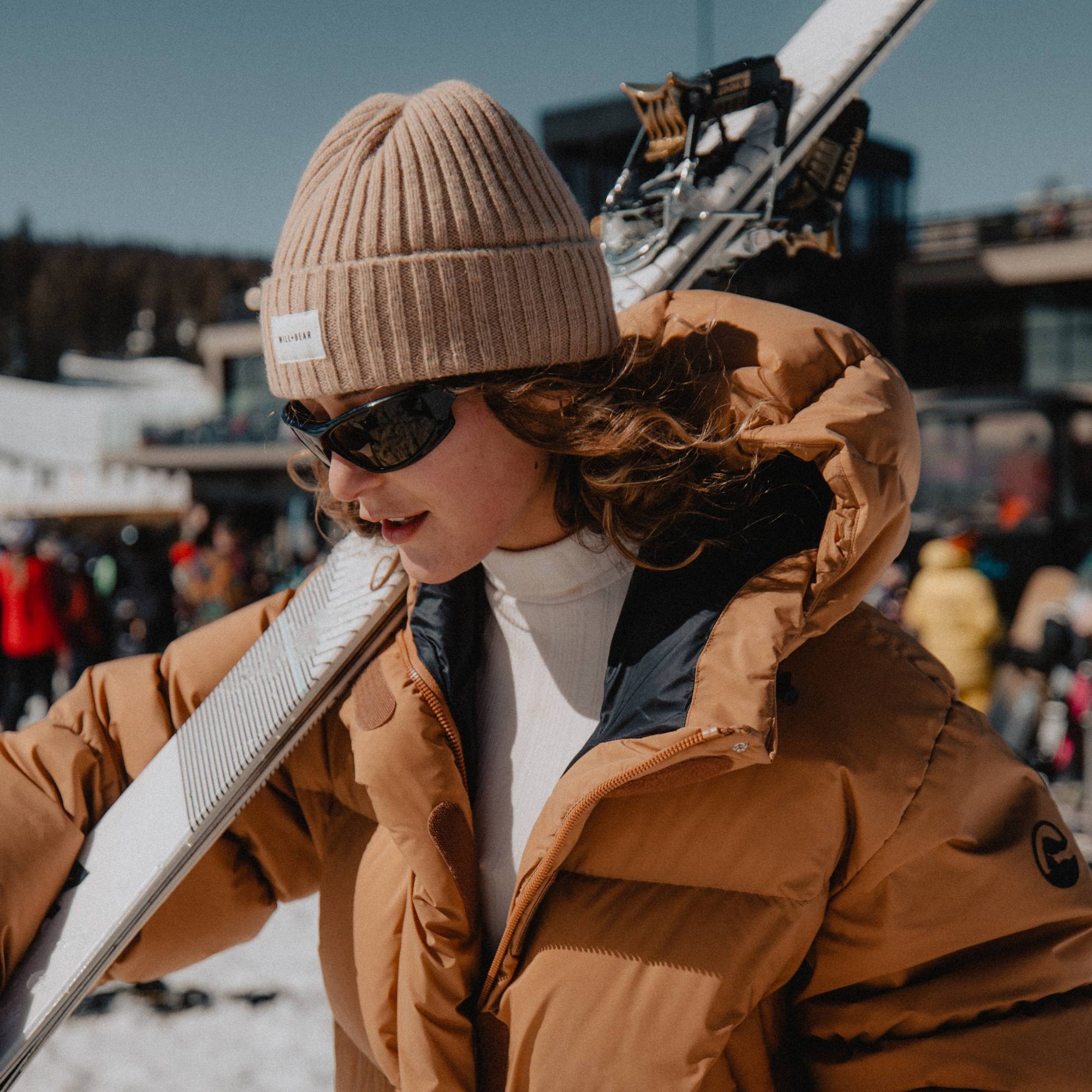 Woman with long, curly hair wearing a beanie at ski slopes