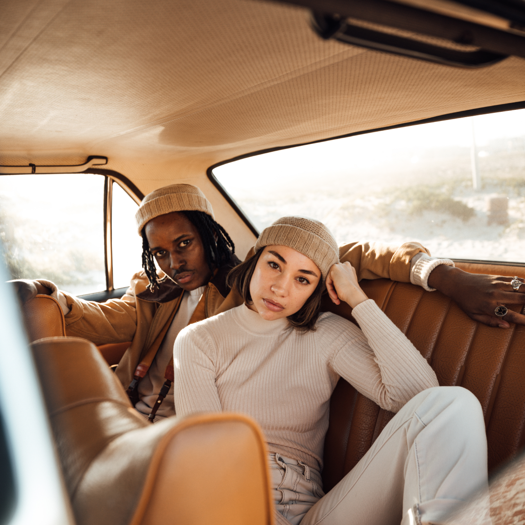 A man and a woman sitting in the back of an old classic car