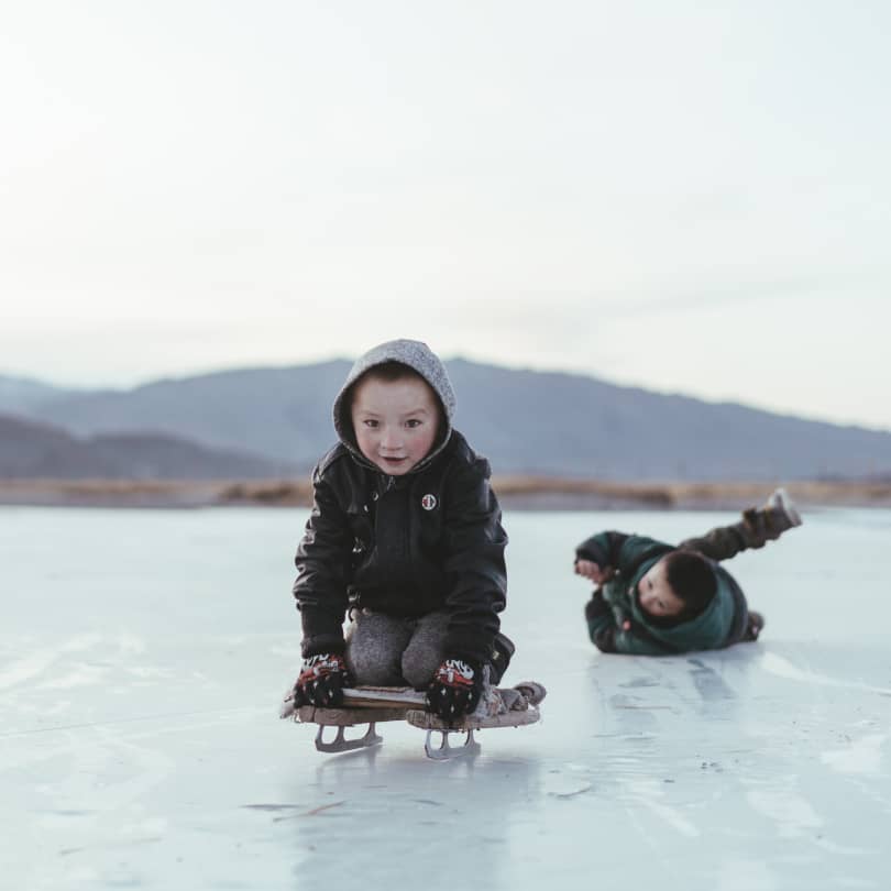 Local Mongolian children playing on the ice on a sled
