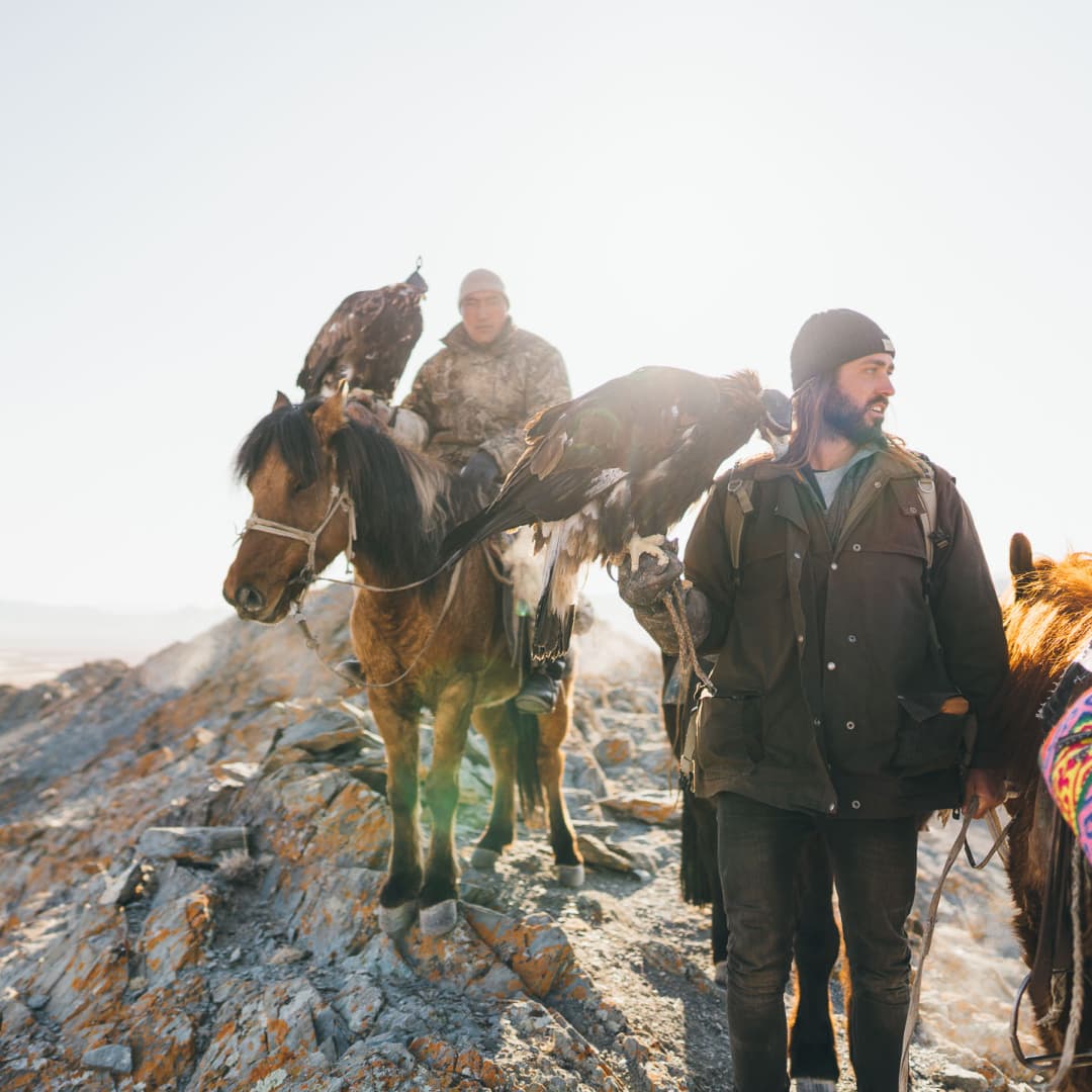 Stefan holding an eagle on his hand outside in Mongolia