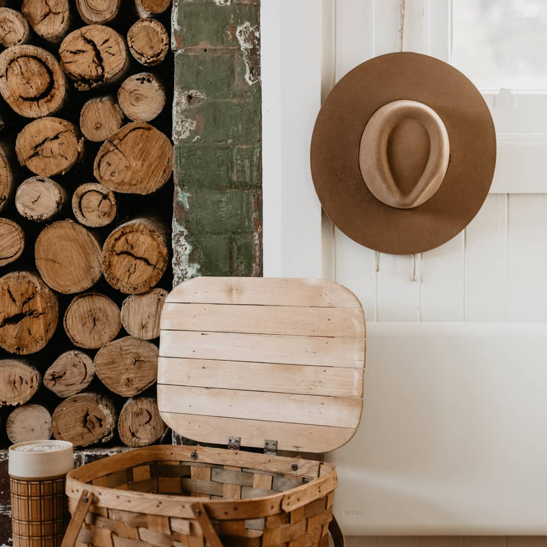 A wide brim hat hanging on the outside wall of a cottage