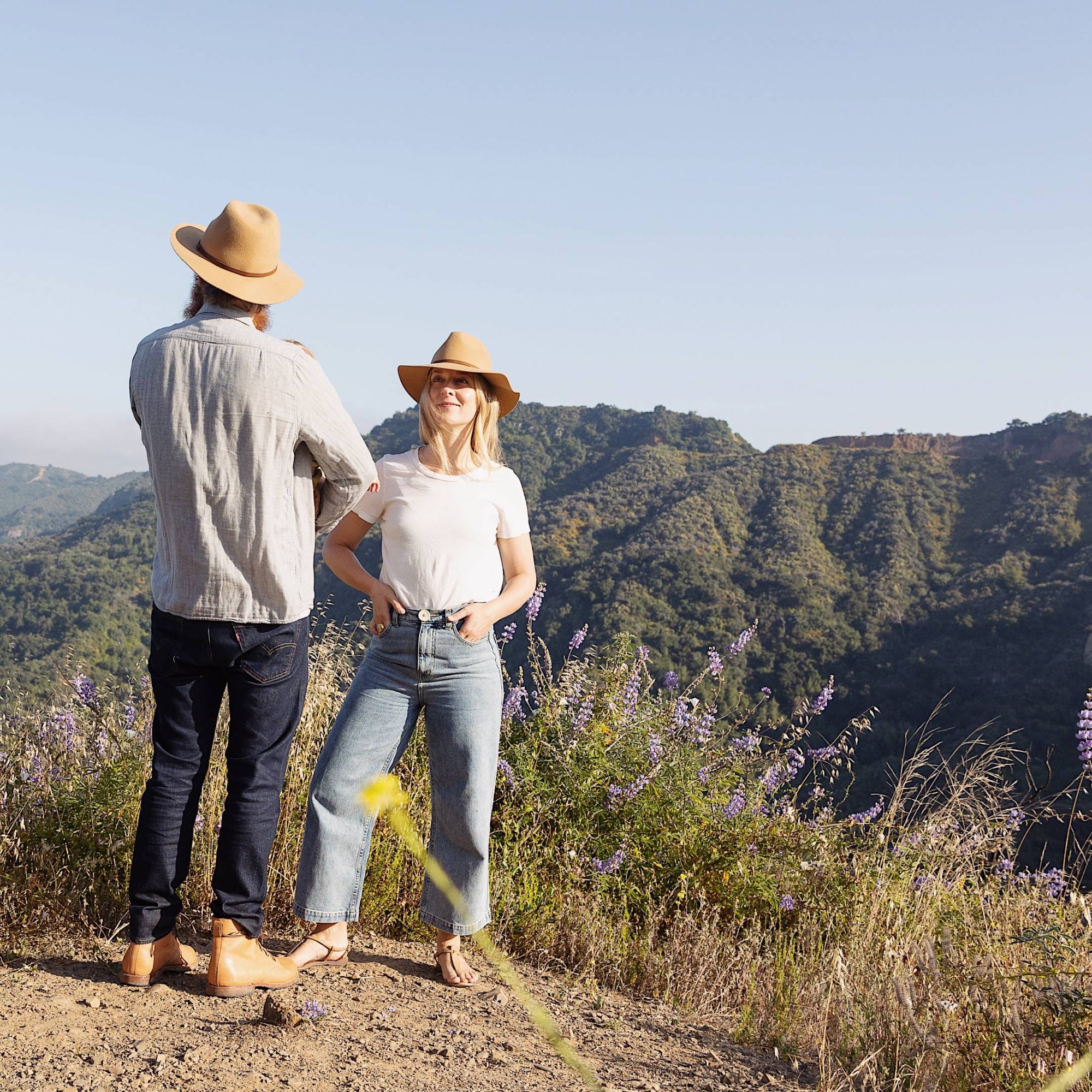 Man and woman wearing wide brim wool hats on top of a mountain