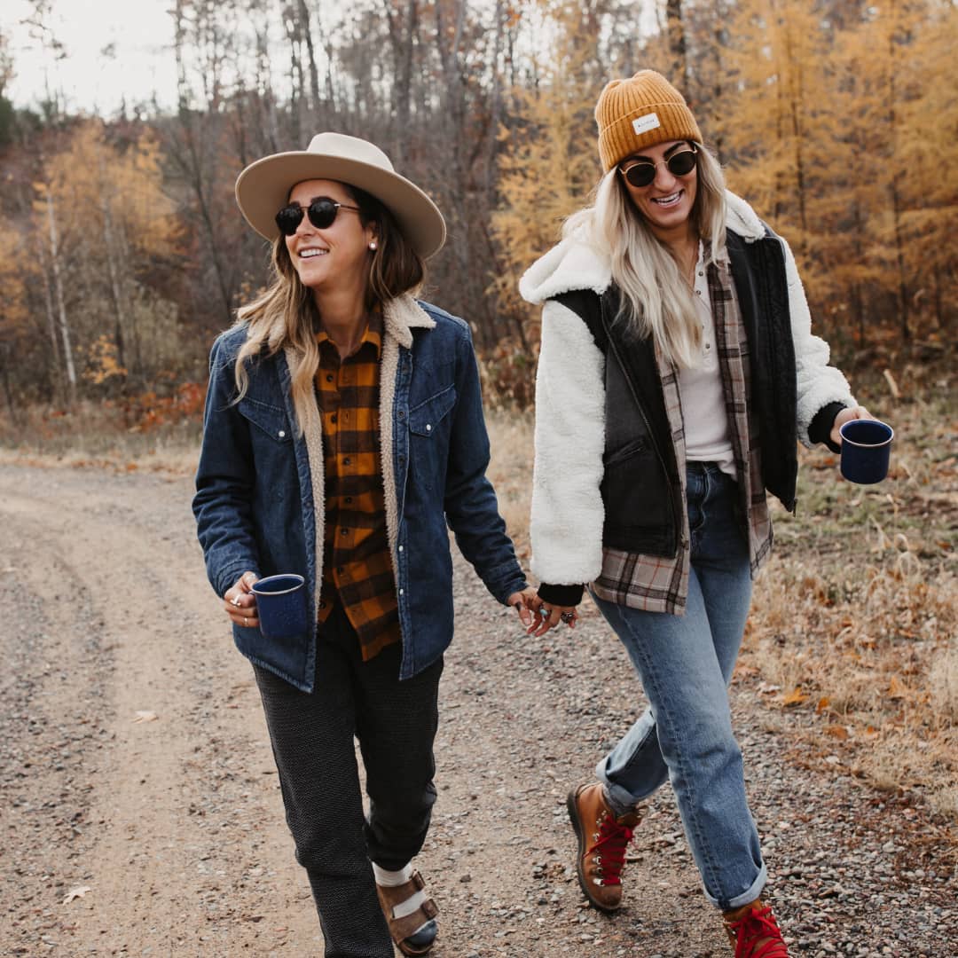 Amanda and Taryn holding hands on a walk holding coffee cups