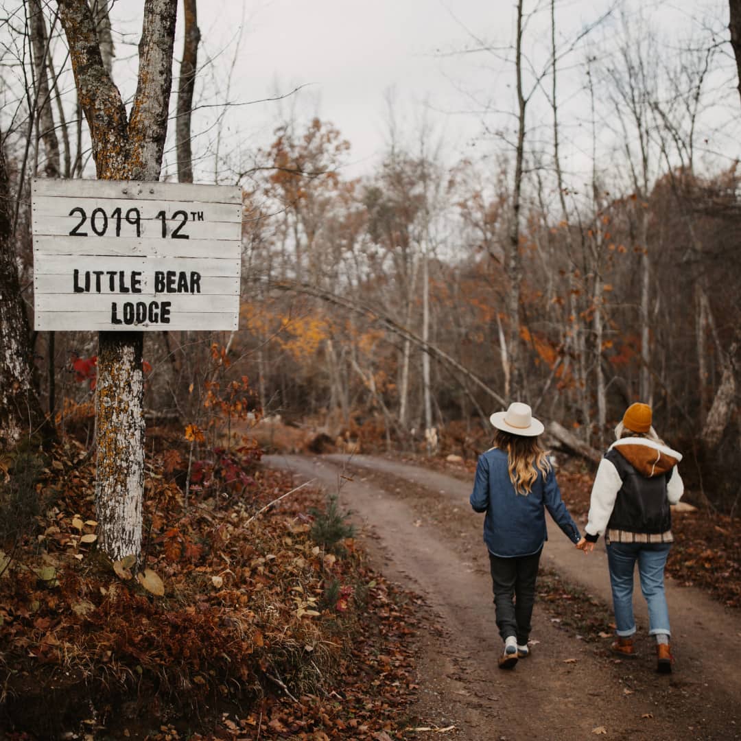 Taryn and Amanda holding hands walking down a road that leads to Little Bear Lodge