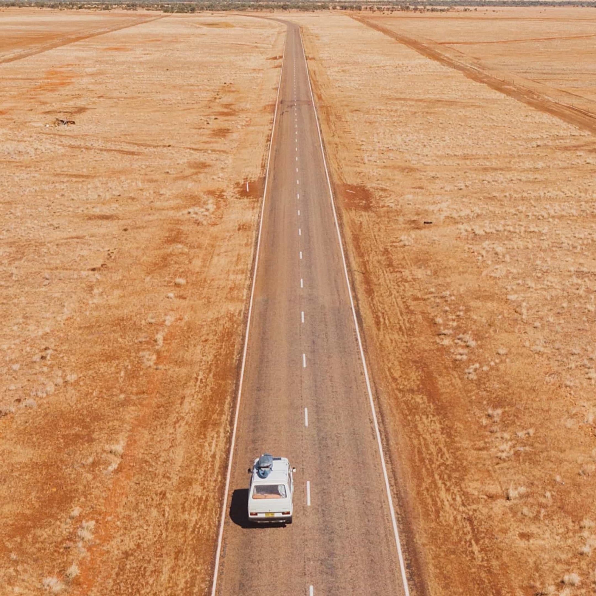 Aerial view of a van driving down a road in the middle of the Australian desert