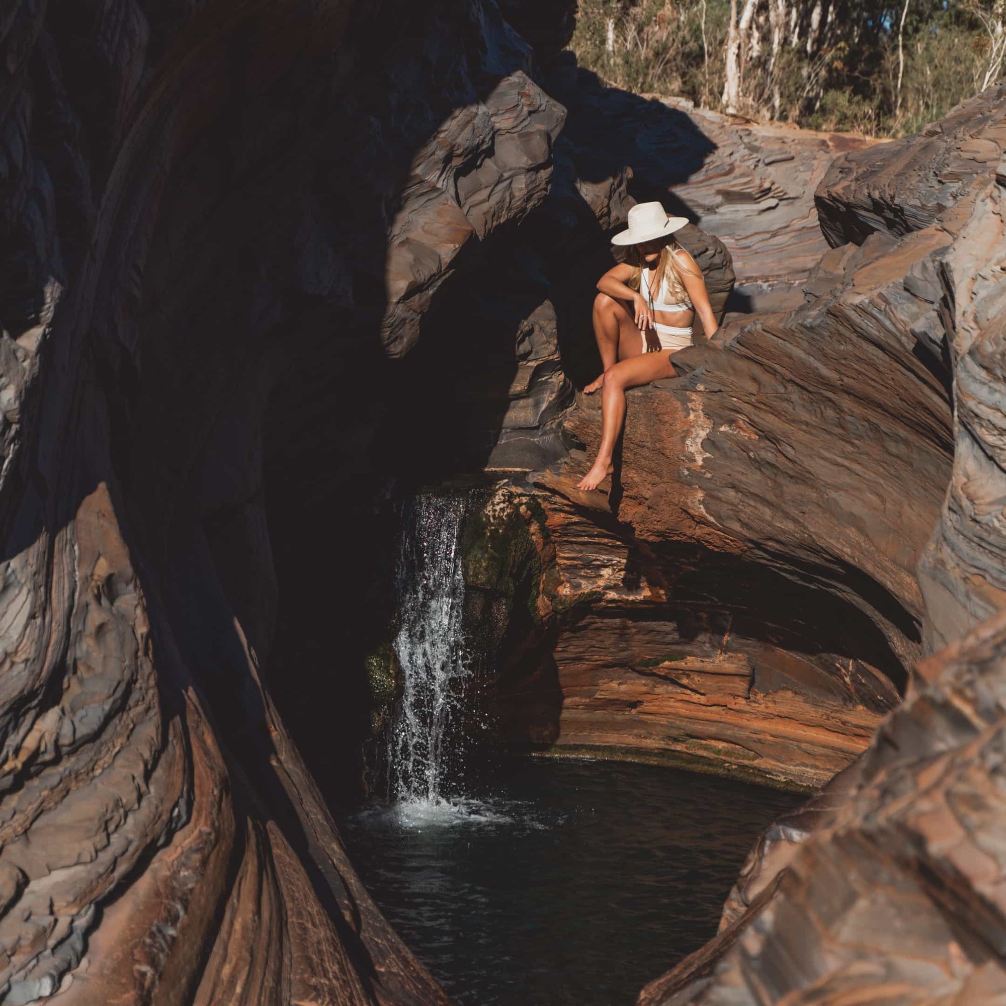 Kendall sitting on the edge of a small waterfall